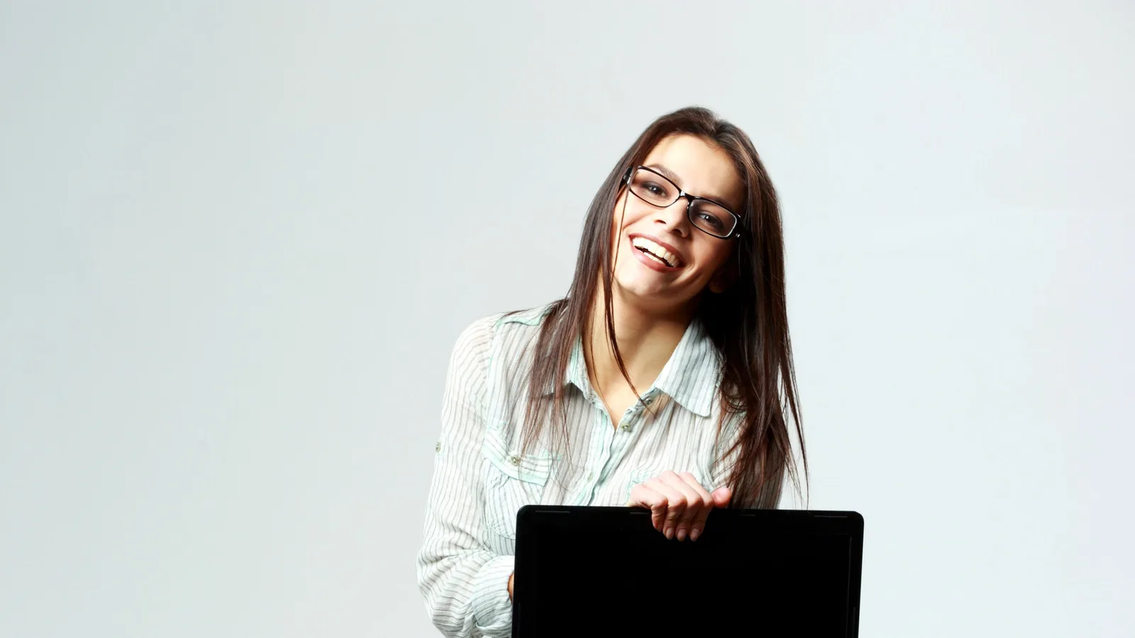 Joyful professional showcasing laptop on neutral background